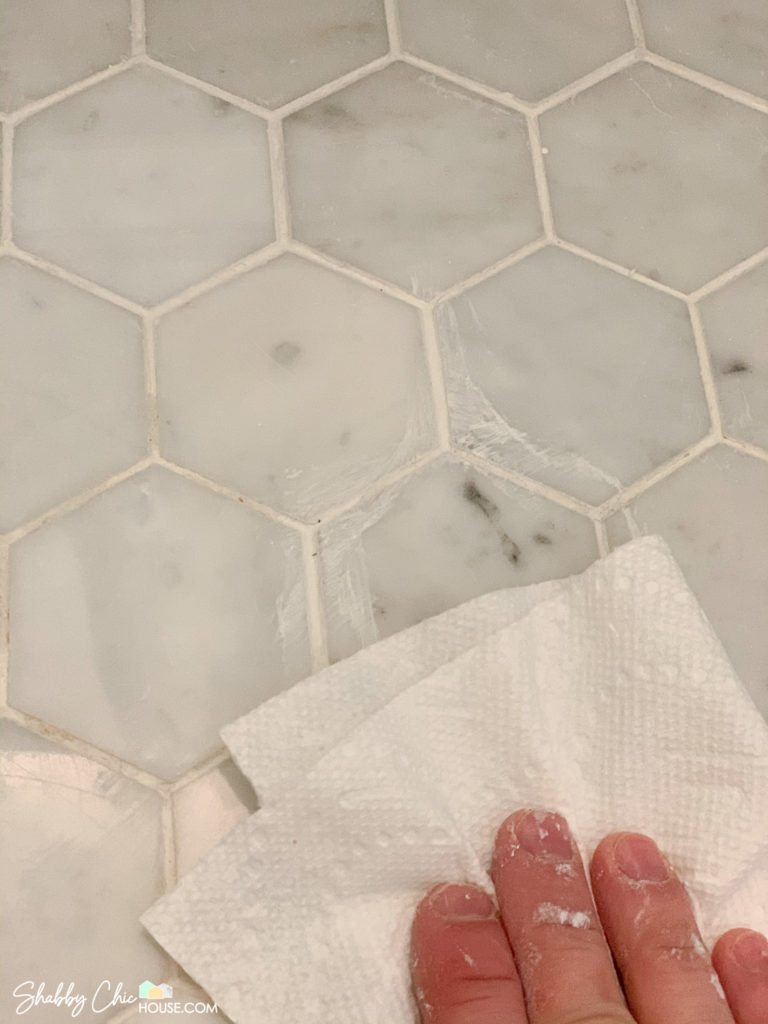 Wiping excess Polyblend colorant with a paper towel as refreshing white tile grout