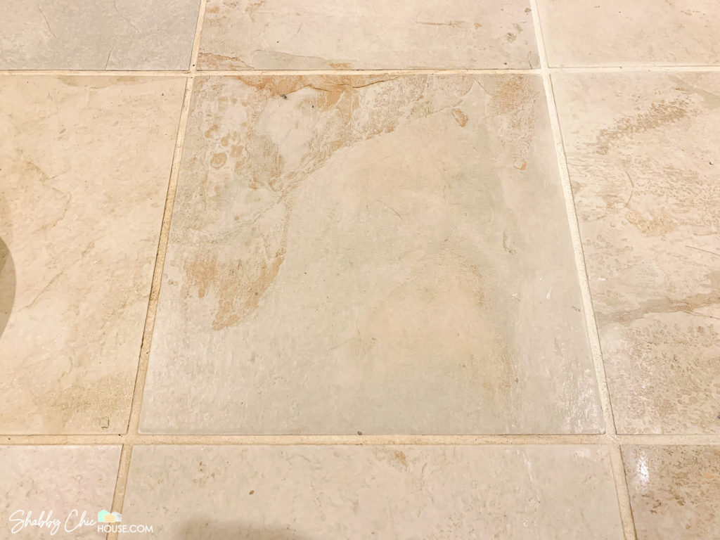 1' x 1' square tile with dirty gross grout on three side and clean painted grout on one side
