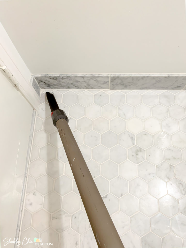 Vacuuming tile floor to pick up debris before grout refresh