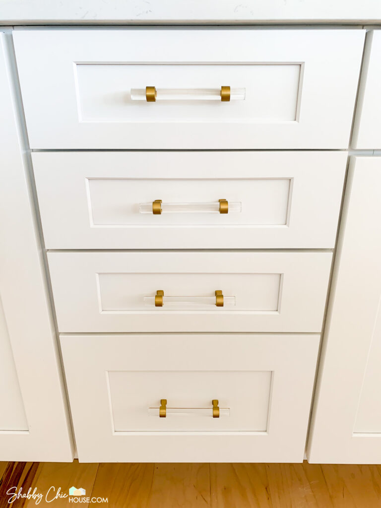 close-up of installed gold and acrylic cabinet handles in white shaker cabinets