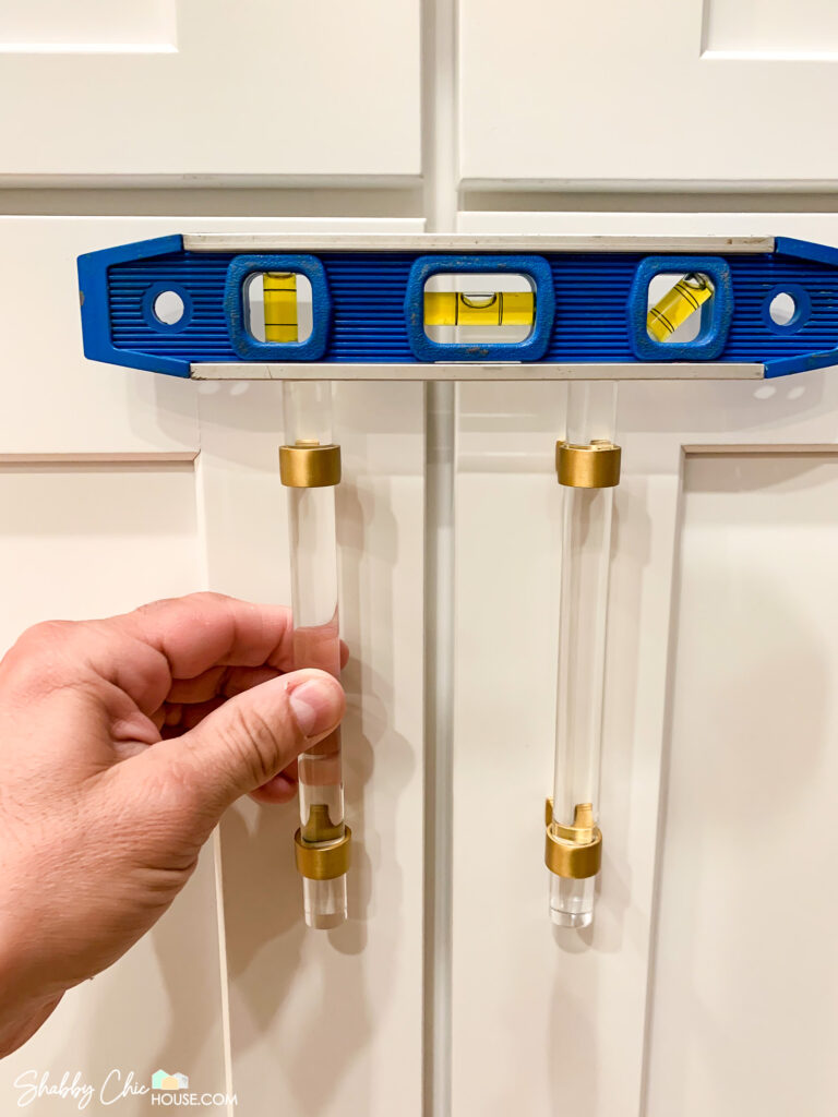 using level to ensure side by side cabinet handles are level - installing cabinet hardware