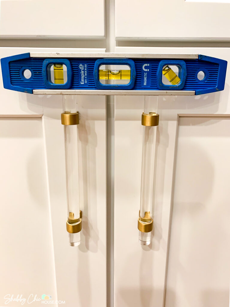 using level to ensure side by side cabinet handles are level - installing cabinet hardware