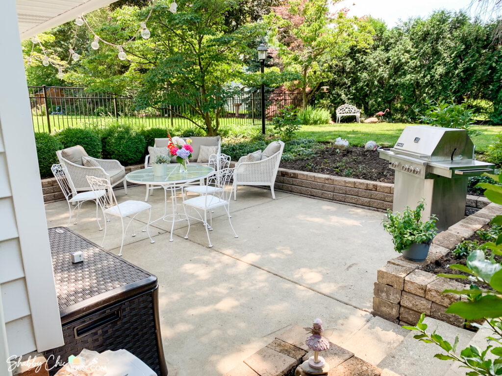 patio after retaining wall has been rebuilt with a grill, wrought iron patio set and cushioned couch & chairs