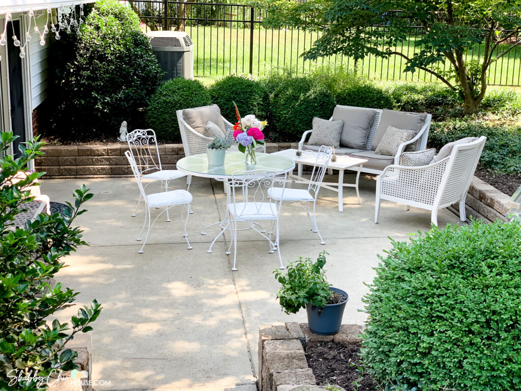 Shot of a patio that has been restored and two patio sets - one white wrought iron patio table and chairs and patio chairs and couch