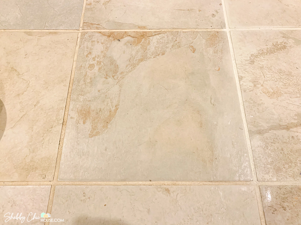 Close-up of a floor tile that has had it's grout on one side (right) cleaned and refreshed with grout colorant. Rest of the tile grout is dirty and gross.