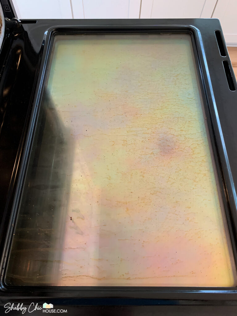 Inside of oven window covered with grease before cleaning hack with The Pink Stuff & a Scrub Daddy.