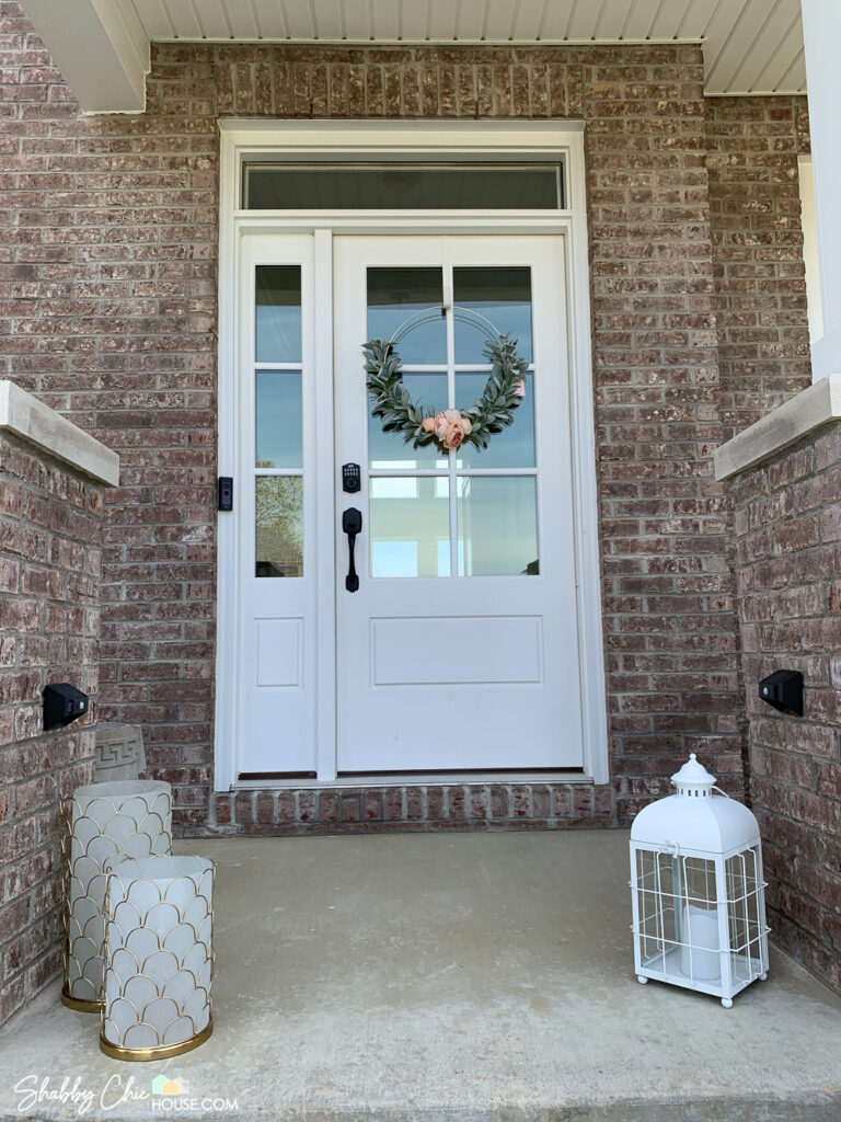 Two Ring solar-powered and motion detecting steplights utilized in a home's exterior entryway with a 6 panel glass door, with sidelight, transom entryway with a brick house exterior and 3 decorative lanterns.