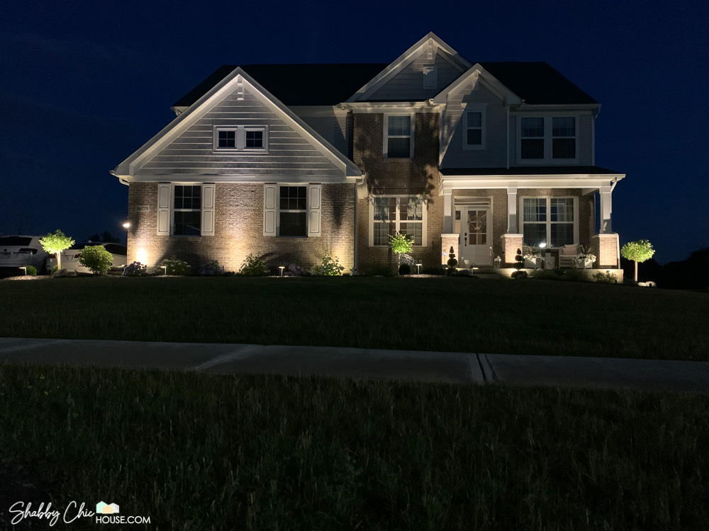 Landscape lighting shot showing the front of a house with uplighting and pathway lights.