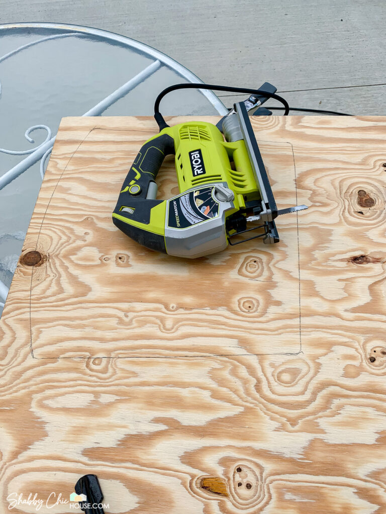 Image of a Ryobi jig saw and a piece of plywood that has the shape of a new seat that will be used as the bottom of a new cushion.