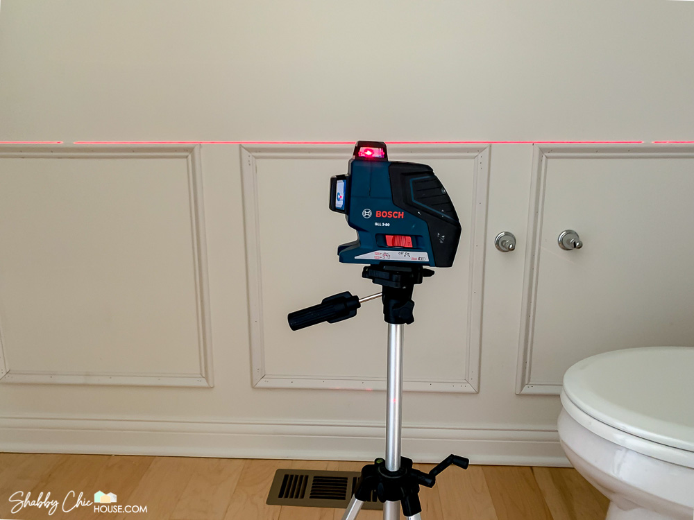Bosch laser level being used to check that three wainscoting boxes are all level to each other.