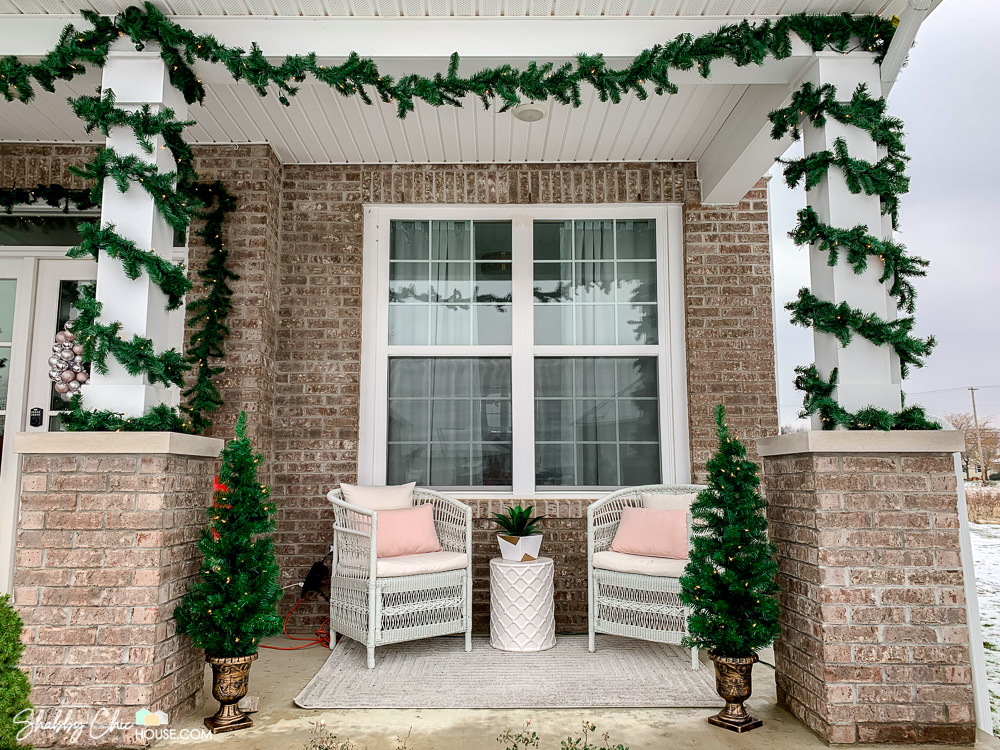 Image of front porch Christmas decorations showing two front porch pillars wrapped with Home Accents 18' pre-lit garland along with two 4' tall Christmas trees from National Tree Company.