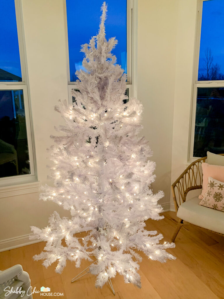 Photograph of a white Christmas tree with half of the Christmas lights not working.