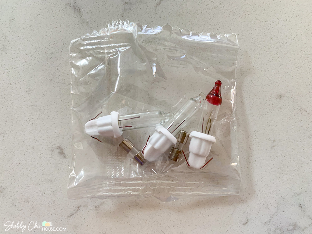 Image of two clear Christmas lights, two fuses and a blinker bulb in a plastic bag for a blog post on how to fix burnt out Christmas tree lights.