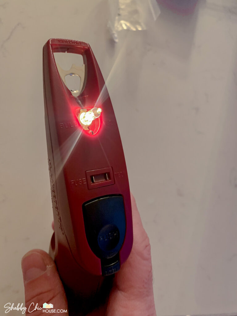 Image showing off the Light Keeper Pro being utilized to quickly test a Christmas light bulb.