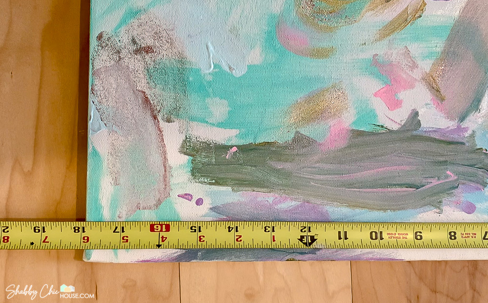 Close-up showing a measurement being taken of a painted canvas for a DIY project on how to build your own floating picture frame.