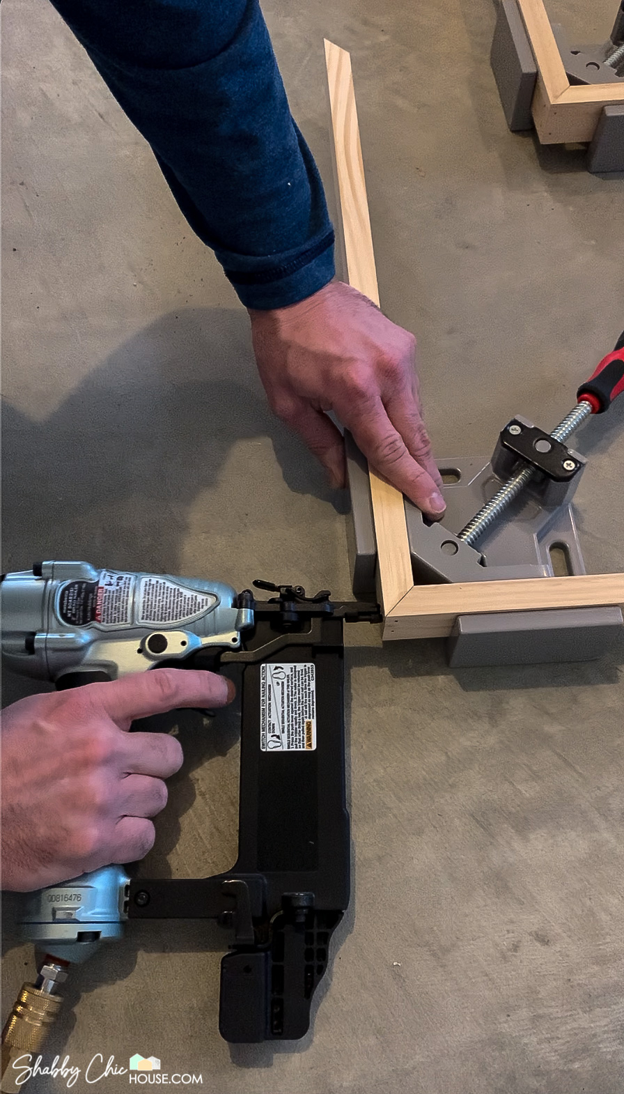 Building a wooden DIY Floating Picture Frame and brad nailing the corners while they are held in place by a 90-degree clamp.