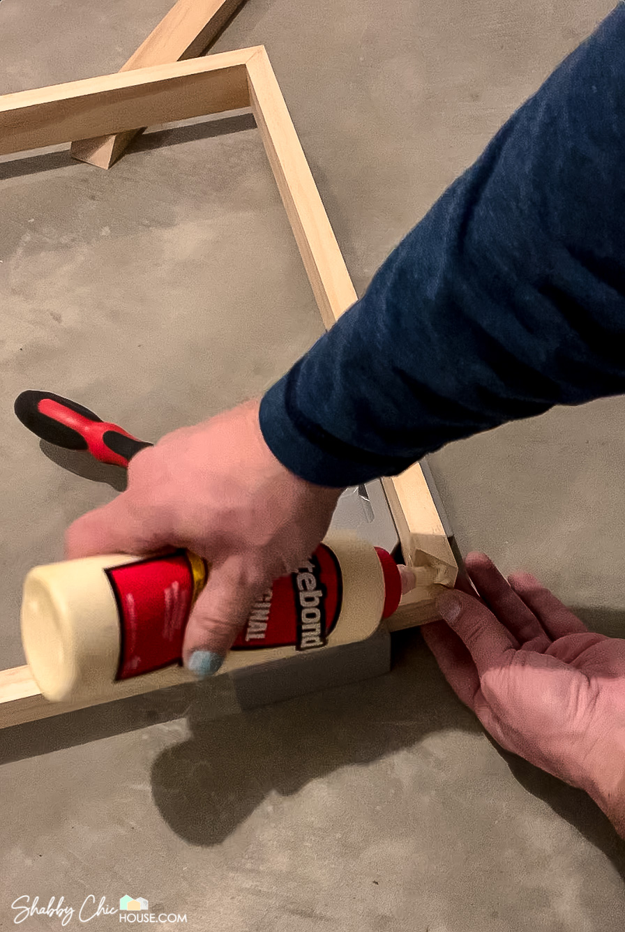 Image showing the application of Titlebond wood glue to the corner miter of a DIY floating picture frame.