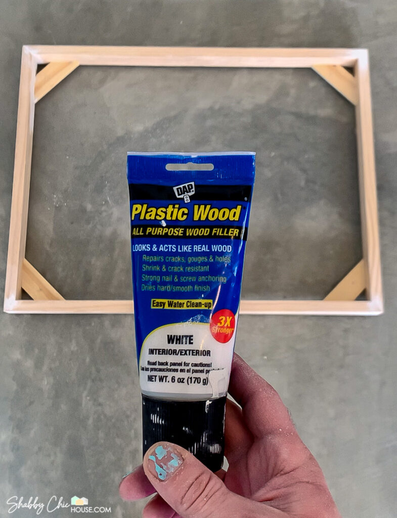 Using DAP Plastic Wood - wood filler to fill the nail holes on a DIY Floating Picture Frame.